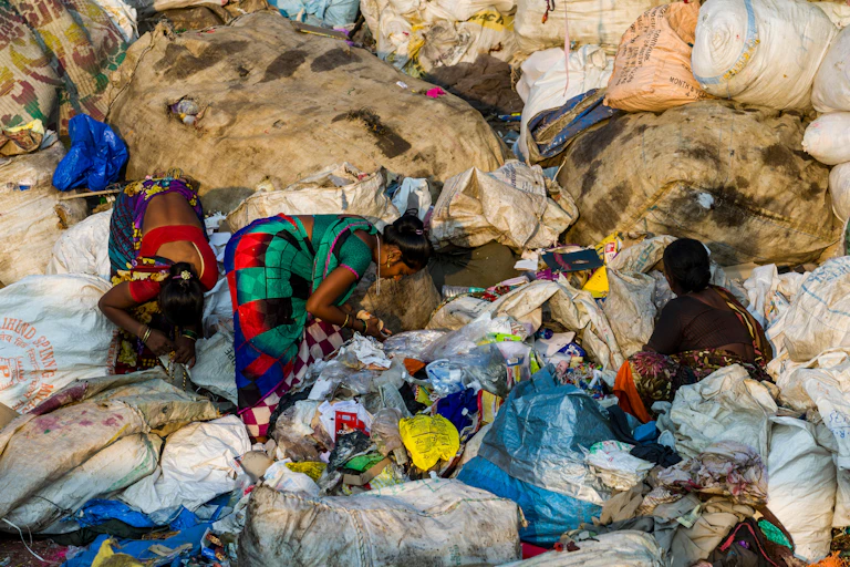 Three women sort through rubbish