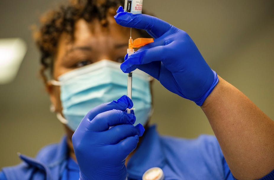 A nurse holds a vial of vaccine.