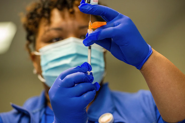 A nurse holds a vial of vaccine.