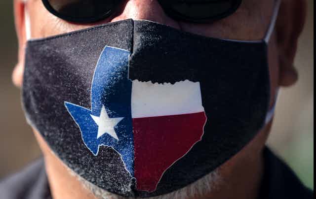A man wears a face mask with the state of Texas on it