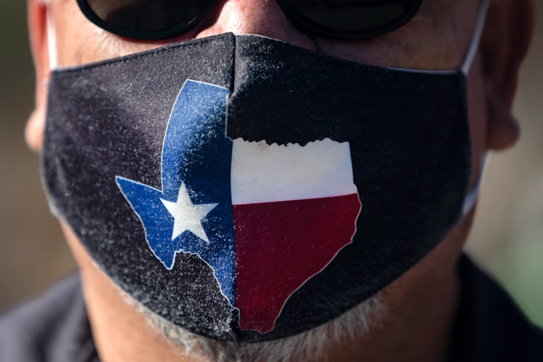 A man wears a face mask with the state of Texas on it
