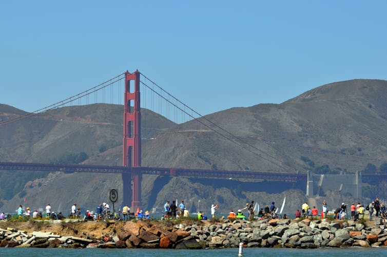 People lined up on the water's edge with the Golden Gate Bridge in the background.