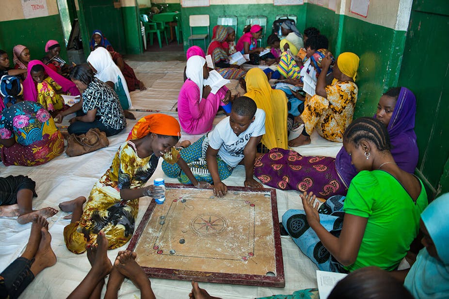 Young women sitting in groups on the floor, playing board games