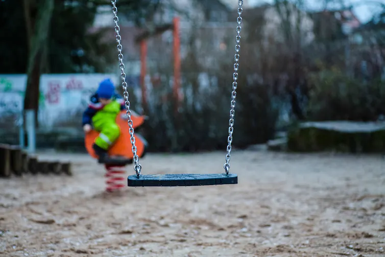 Une balançoire vide dans une cour de récréation vide