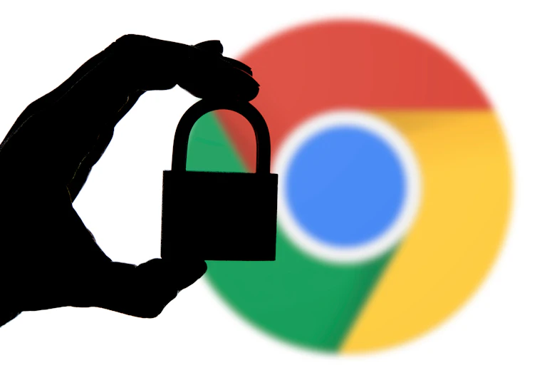 A hand holding a padlock in front of the Google Chrome icon