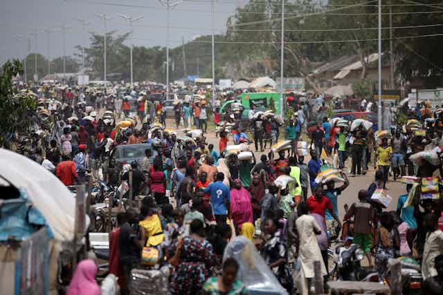 People carry bags of food on their heads during a mass looting of a warehouse that have COVID-19 food palliatives that were not given during lockdown to relieve people of hunger, in Abuja, Nigeria, on October 26, 2020.
