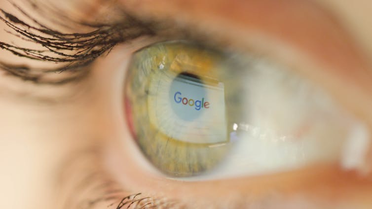 An eye reflects the Google logo