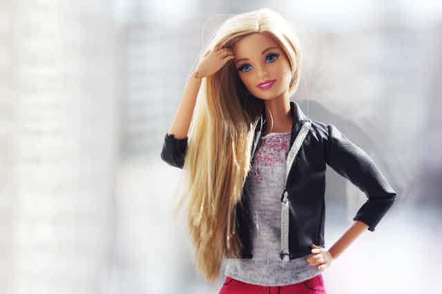 A barbie doll with blonde hair and her hand on her hip.