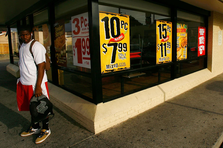 A boy stands next to a fast-food restaurant.