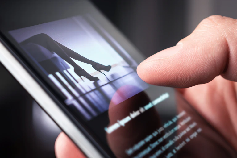 A man looks at a photo of a woman in high heels on his phone.