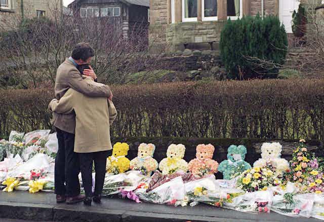 People visit flowers laid for the victims of the Dunblane shooting.