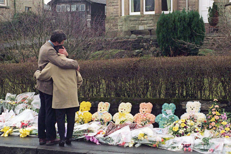 People visit flowers laid for the victims of the Dunblane shooting.