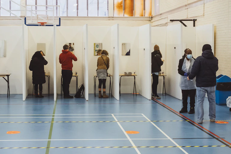 People line up in cubicles to take a Covid-19 lateral flow test in south London, England.
