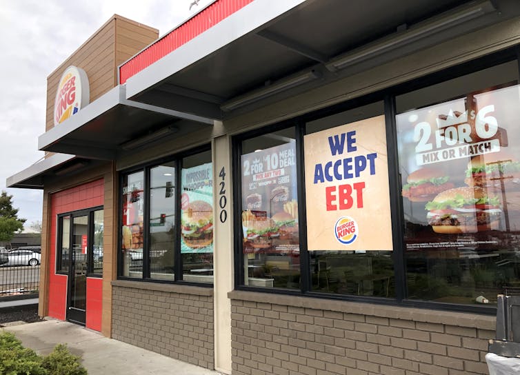 A Burger King outlet displaying a 'We Accept EBT' poster in the window.