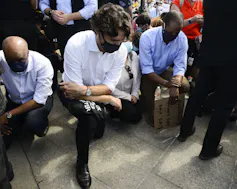 Justin Trudeau takes a knee while wearing a face mask.