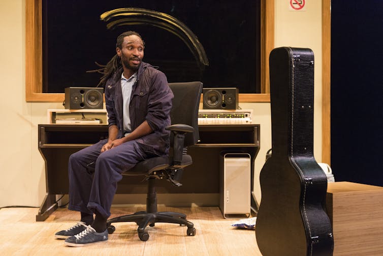 A black man looks at a propped up guitar case