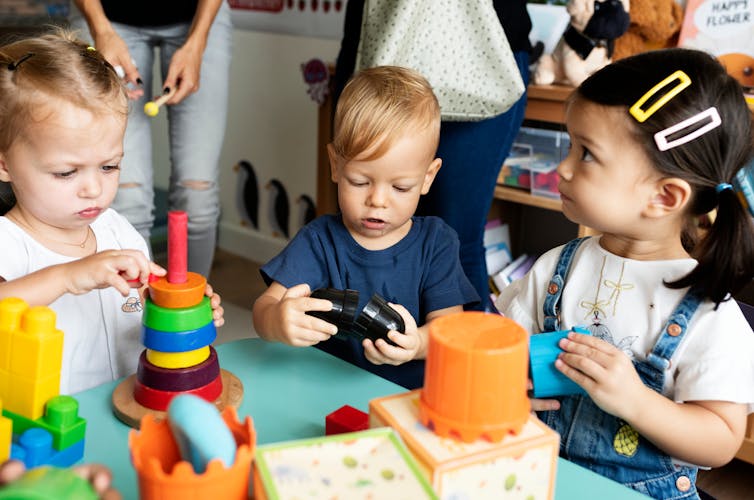 Three young children playing with various toys.