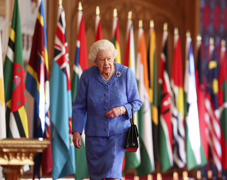 The Queen walking past Commonwealth flags at Windsor Castle.