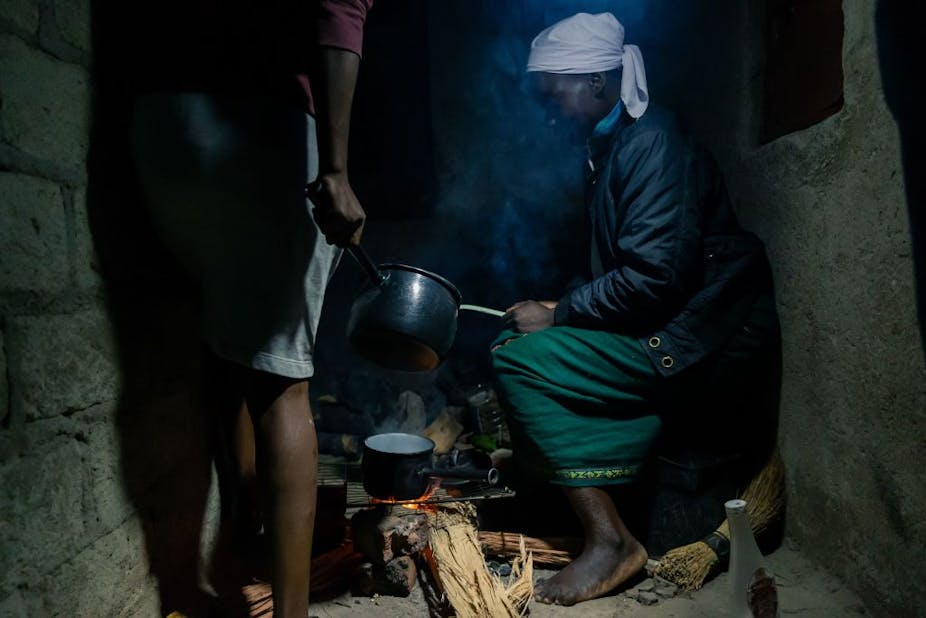 A woman cooks on wood fuel.