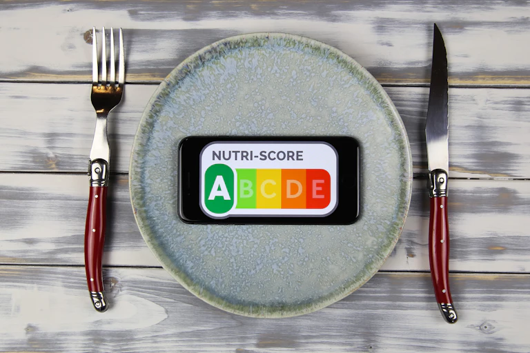 Plato con etiqueta de clasificación nutricional NutriScore falnqueado por cuchillo y tenedor.