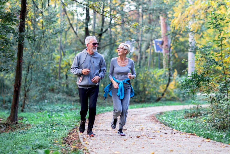 Older man and older woman jogging in the woods.