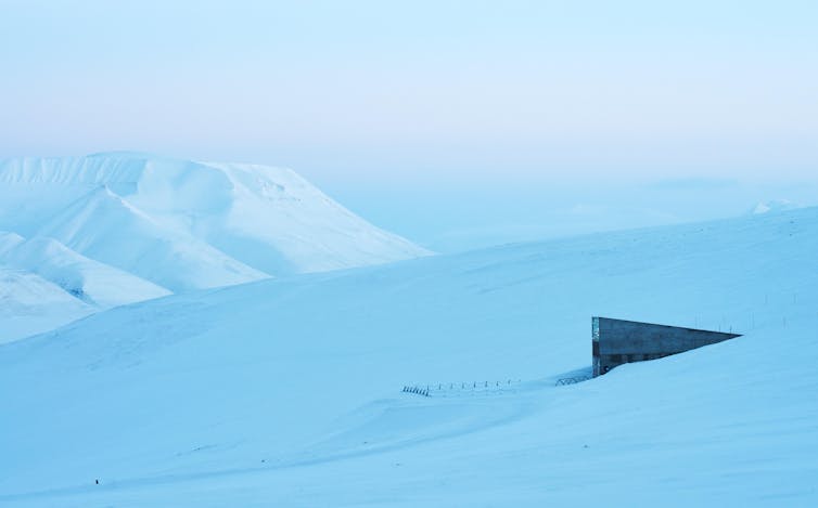 A dark concrete structure rises out of a snowscape.