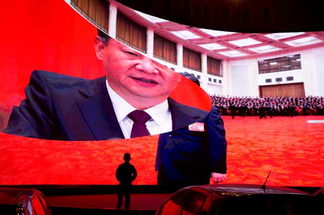 A child stands near a large screen showing photos of Chinese President Xi Jinping.