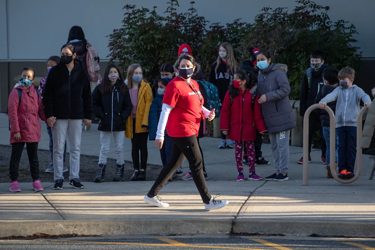 A teacher walking and children looking.