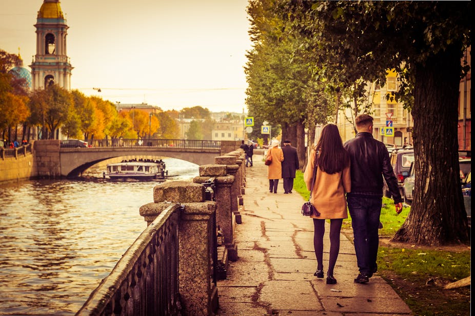 Two couples walk along a canal.