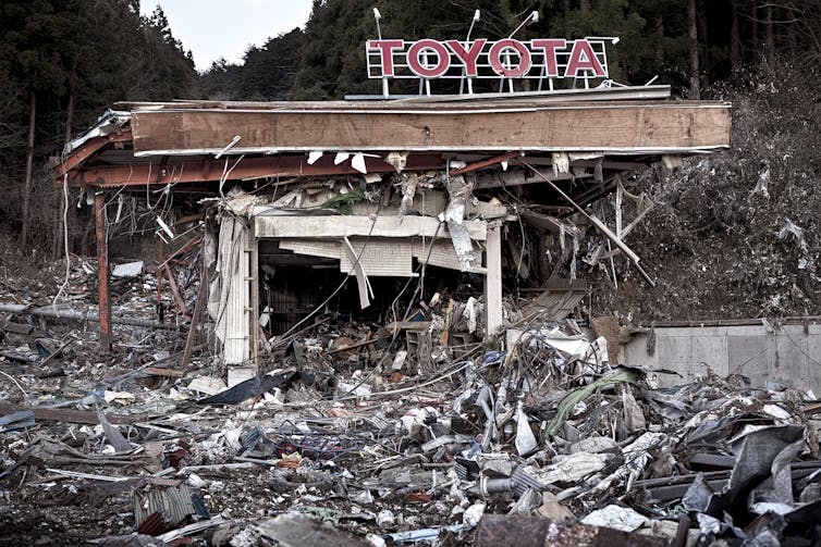 A Toyota sign hanging over a pile of rubble, caused by the Fukushima disaster.