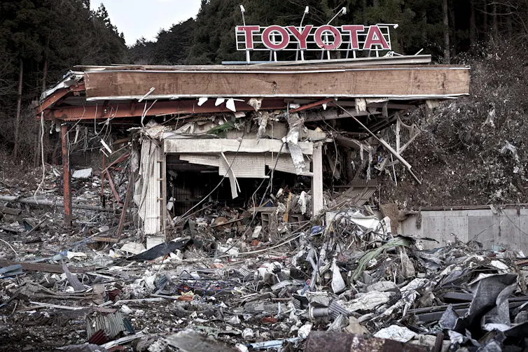 A Toyota sign hanging over a pile of rubble, caused by the Fukushima disaster.