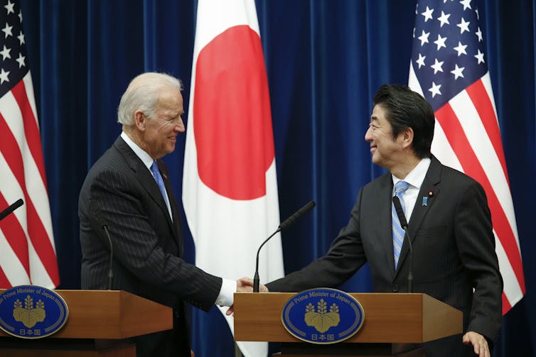 The then US vice president Joe Biden shakes hands with Japanese prime minister Shinzo Abe at a meeting in Tokyo, 20131. In the background are US and Japanese flags.