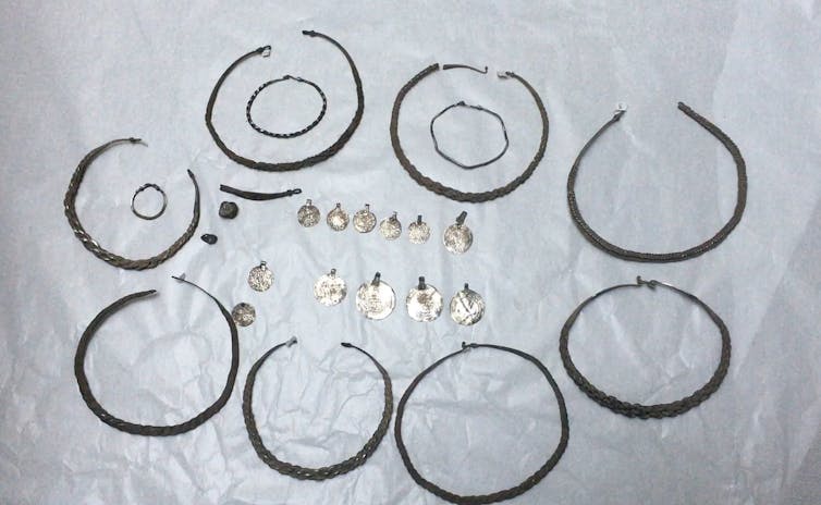 Several worn silver chain necklaces and coins.