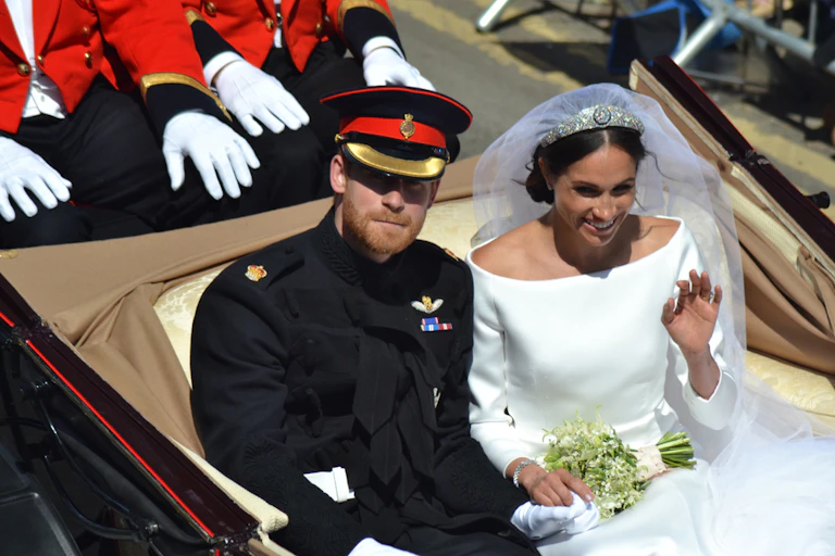 Prince Harry and Meghan in wedding outfits riding in carriage
