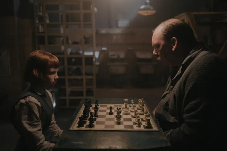 A girl and man playing chess.
