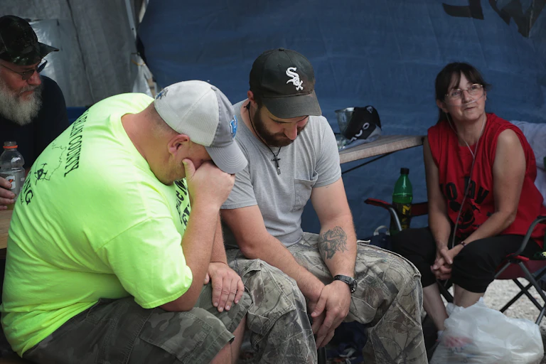 Two exhausted unemployed coal miners and a woman, sitting
