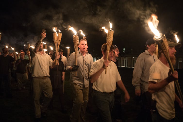 Torch-bearing white men marching at night, shouting