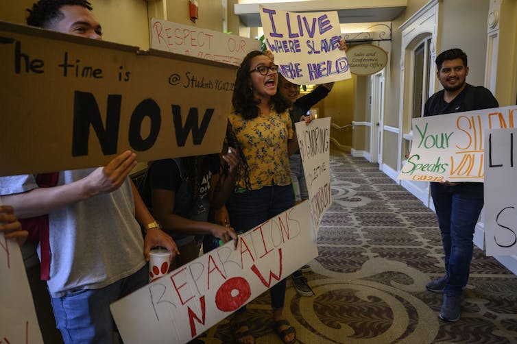 Protesters hold signs calling for reparations for U.S. slavery