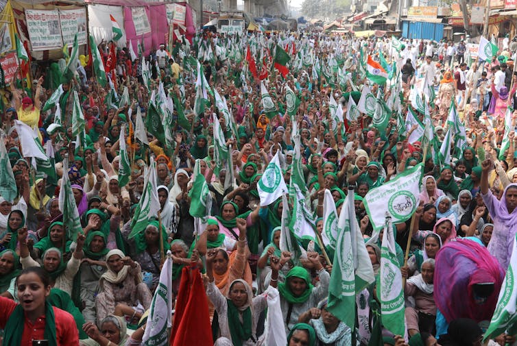 Crowd of hundreds of women holding green flags and raising their fists in the streets