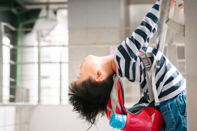 Hyperactive boy climbing ladder wearing backpack