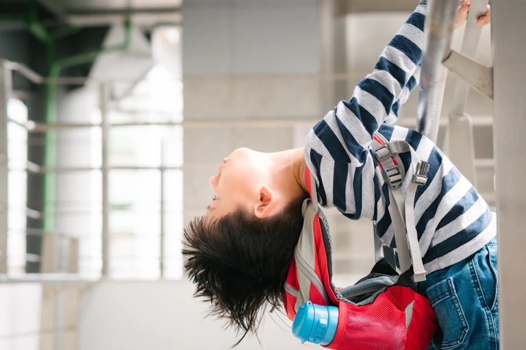 Hyperactive boy climbing ladder wearing backpack