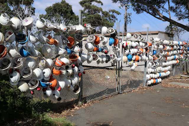 Hard hats hanging on a gate