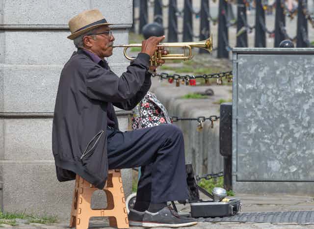 A seated trumpeter busks in Liverpool. 