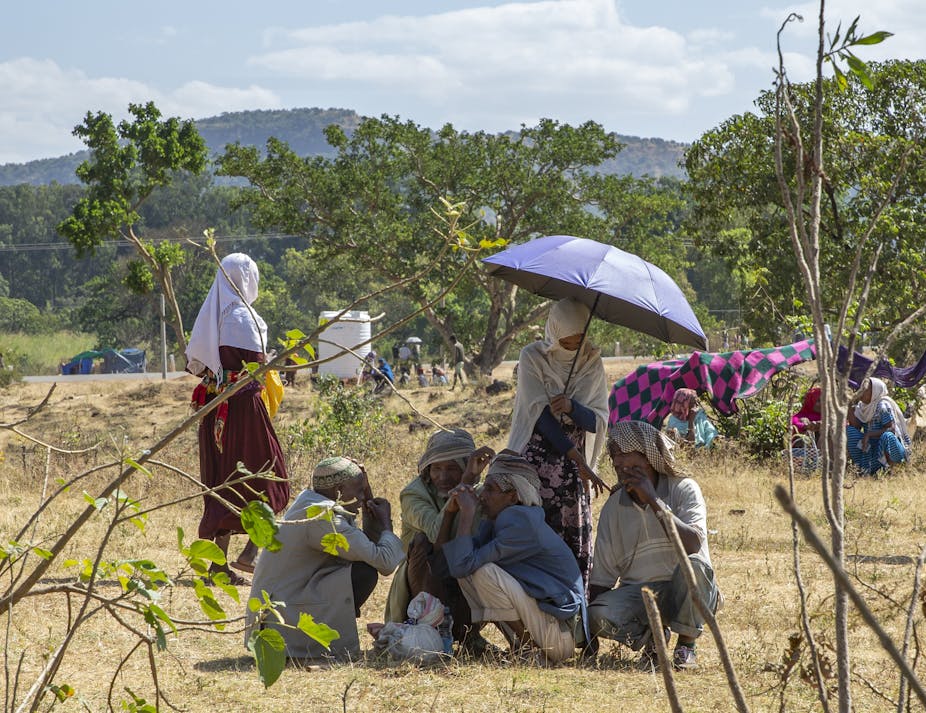 Men and women huddled under an umbrella