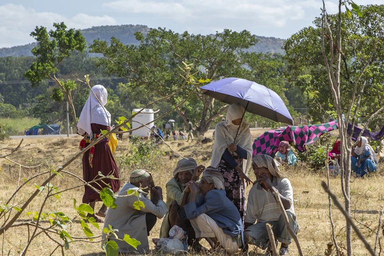 Men and women huddled under an umbrella