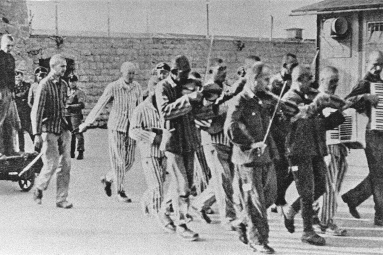 A group of prisoners march and play instruments as they lead a boy to execution.