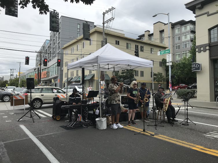 A band plays under a gazebo on a street closed to traffic.
