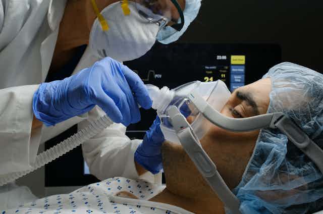 A clinician adjusts a patient's oxygen mask