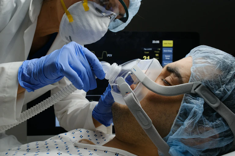 A clinician adjusts a patient's oxygen mask