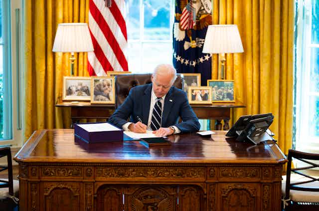 President Biden signing the COVID relief bill at his Oval Office desk